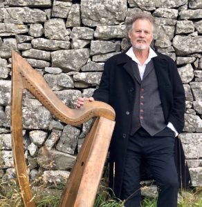 Image of Patrick Ball leaning against a wall with a harp.