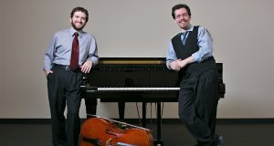 Two men standing on other side of a piano