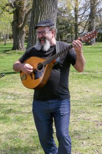 Man standing outside holding a stringed instrument.