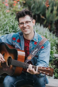A man sitting outside holding a guitar